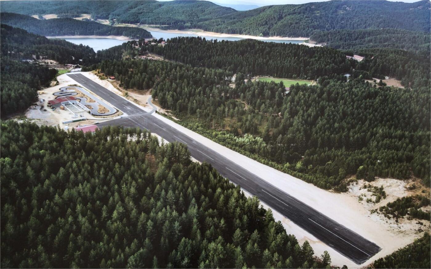 Vista aerea della pista dell'aviosuperficie Franca tra le pinete della Sila, con il lago Ampollino sullo sfondo